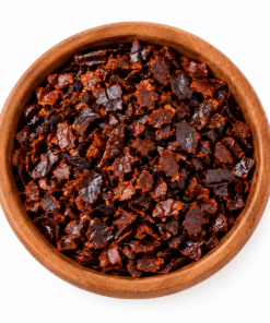 Ancho chili gebroken in houten kom op witte achtergrond