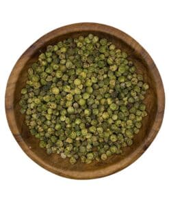 Gedroogde groene peperkorrels in een houten kom op witte achtergrond