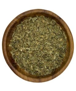 Houten kom gevuld met gedroogd fenegriekblad (kasoori methi) op een witte achtergrond.
