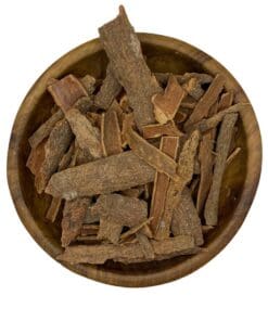 Houten kom gevuld met gedroogde Cassia-kaneelbast op een witte achtergrond.