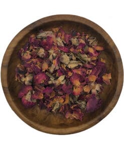 Gedroogde roze rozenknopjes in een houten kom op een lichte achtergrond