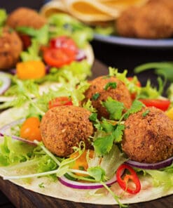 Falafel kruidenmix gebruikt op verse falafelballetjes met sla, tomaat en citroen op een wrap.