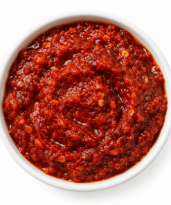 Rode harissa peperpasta in een witte ronde kom