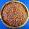 Houten kom gevuld met grof keukenzout, Hawaii Zout Rood – Alea Rood Gold, op een blauwe achtergrond.